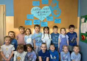Dzieci stoją przed tablicą informacyjną o autyzmie