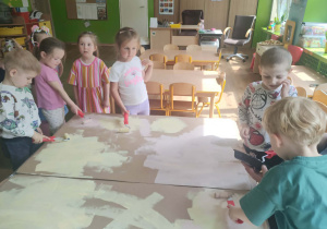 Dzieci malują karton wałkami