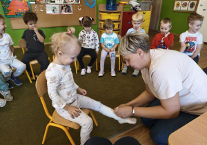 Pani zawija nogę dziewczynki w bandaż