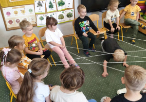 Dzieci przechodzą pod pajęczą siecią z włóczki