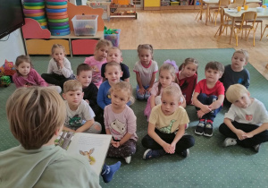 Dzieci słuchają książki czytanej przez chłopca