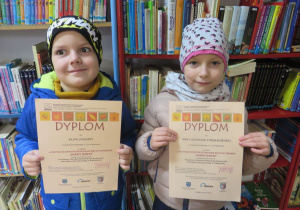chłopiec i dziewczynka prezentują swoje dyplomy za udział w konkursie