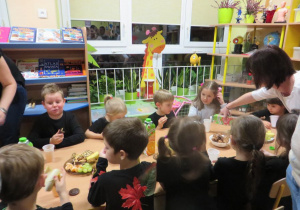 dzieci siedzą przy stole podczas poczęstunku
