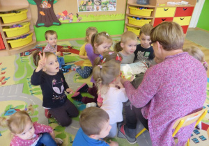Dzieci z uwagą słuchają książki czytanej przez babcię chłopca