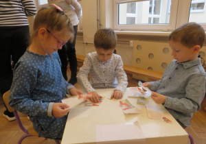 Troje dzieci układa puzzle na konursie
