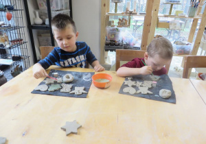 Dwóch chłopców maluje gotowe ozdoby ceramiczne