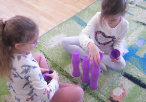Dziewczynki budeują wieże z fioletowych kubków