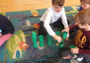 Troje dzieci buduje wieże z zielonych kubków