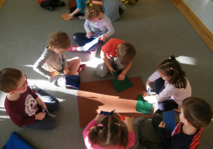 Dzieci z grupy II wycinają z filcu ubrania dla swoich misiów narysowanych na kartonach