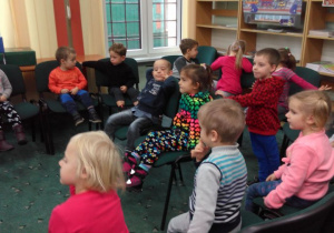 dzieci słuchają opowiadania , które czyta im pani z biblioteki
