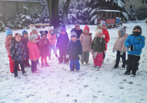 Uśmiechnięte przedszkolaki z grupy II pozują do zdjęcia na śniegu
