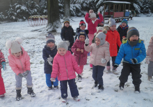 Przedszkolaki rzucają do góry śniegiem