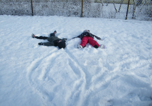 Dwoje dzieci robi aniołka na śniegu
