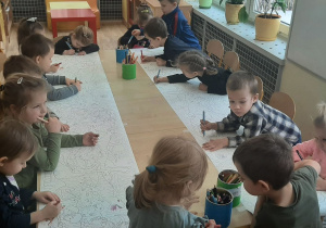 Dzieci z grupy II kolorują obrazek z dinozaurami