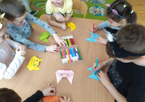 Dzieci z grupy IV malują swoim kotom z origami oczy, buzię i nos