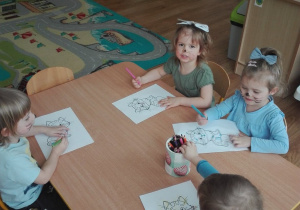 Czworo dzieci z grupy I koloruje rysunek kota