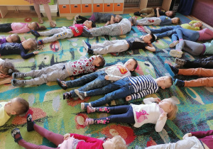 Przedszkolaki z grupy II i V leżą na dywanie i słuchają kołysanki
