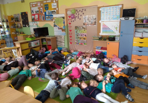 Dzieci z grupy I i IV leżą na dywanie i słuchają kołysanki