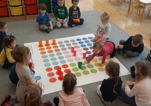 Dzieci z grupy II dopasowują kolorowe kubeczki do kolorów na macie do kodowania
