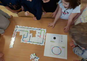 Przedszkolaki z grupy V oglądają jak porusza się ozobot po puzzlach ułożonych przez dzieci