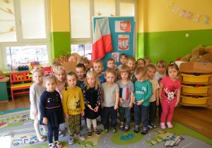 Dzieci z grupy I stoją na tle tablicy z polskimi symbolami narodowymi