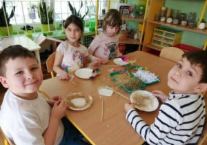 Czworo dzieci wykonuje gniazdo z talerzyków papierowych i rafii