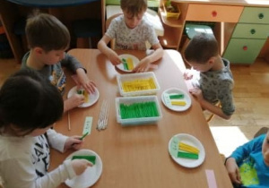 Piątka dzieci wykonuje zadanie matematyczne - za pomocą patyczków w dwóch kolorach ilustruje działanie podane przez nauczyciela
