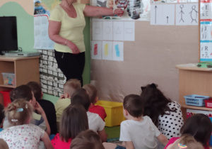 Pani nauczycielka pokazuje dzieciom etapy powstawania książki na tablicy demonstracyjnej