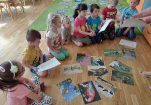 Dzieci młodsze oglądają obrazki zwierząt, które mają pokolorować