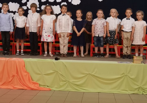Jedenaścioro dzieci sześcioletnich stoi na scenie