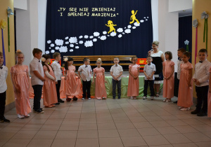 Dzieci stoją w półkolu i kłaniają się po zatańczeniu poloneza