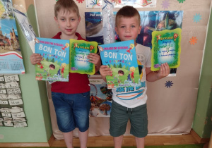Dwóch chłopców poakzuje nagrody - książkę i latawiec