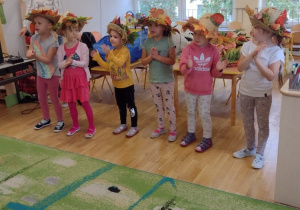 Sześć dziewczynek z grup starszych ubrane w jesienne kapelusze tańczą do piosenki śpiewanej przez panią Ulę