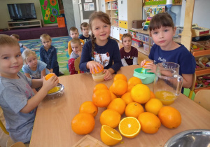 Dwie dziewczynki i jeden chłopiec wyciskają sok z pomarańczy