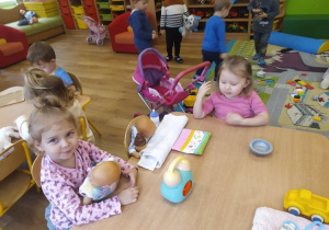 Dziewczynki bawią się lalkami przy stoliku