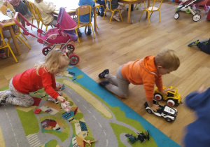 Dwoje dzieci bawi się autami