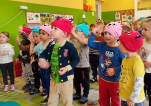 Dzieci z grupy I tańczą do piosenki o kotku, część z nich ma kolorowe czapki z buzią kotka