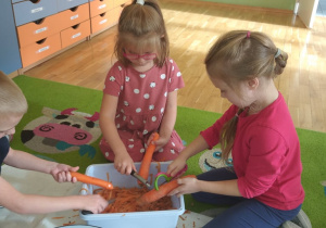 Troje dzieci obierac marchewki