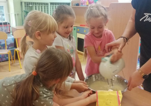 Dziewczynka mikserem miesza ciasto przy pomocy nauczycielki