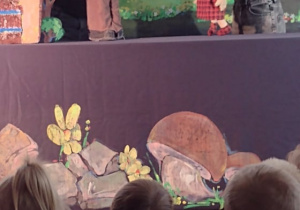 Dzieci oglądają na scenie rozmowę kukiełki Małgosi i taty