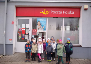 Dzieci stoją przed budynkiem poczty