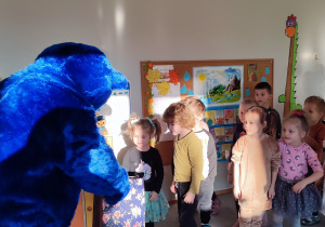 Dzieci z grupy II częstują się suszonymi jabłuszkami, które rozdaje postać niebieskiego pluszowego misia