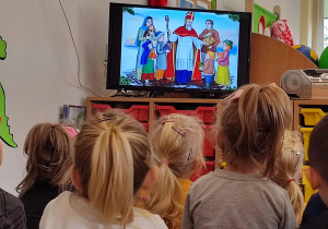Dzieci siedzą przed telewizorem i oglądają bajkę o świętym Mikołaju