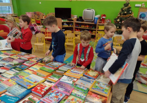 Dzieci z grupy V oglądają książki, które będą w nowej bibliotece przedszkolnej