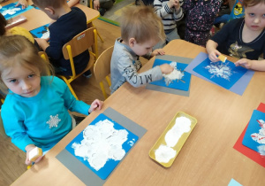Dzieci z grupy I malują śnieżynki białą farbą
