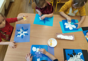 Przedszkolaki z grupy I malują białą farbą śnieżynki