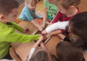 Dzieci szukają ukrytych skarbów w misce z piaskiem