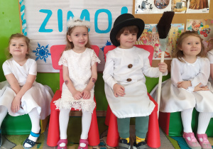 Czworo dzieci przebrane całe na biało do występu, jeden chłopiec jest bałwankiem, a jedna dziewczynka Zimą