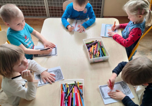Pięcioro dzieci z grupy II koloruje papierowe tablety