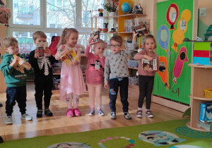 Sześcioro dzieci z grupy pierwszej pokazuje produkty żbożowe podczas piosenki śpiewanej przez panią Ulę
